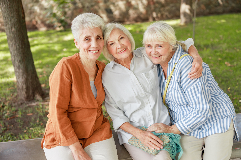 Three senior women sitting close together on a bench