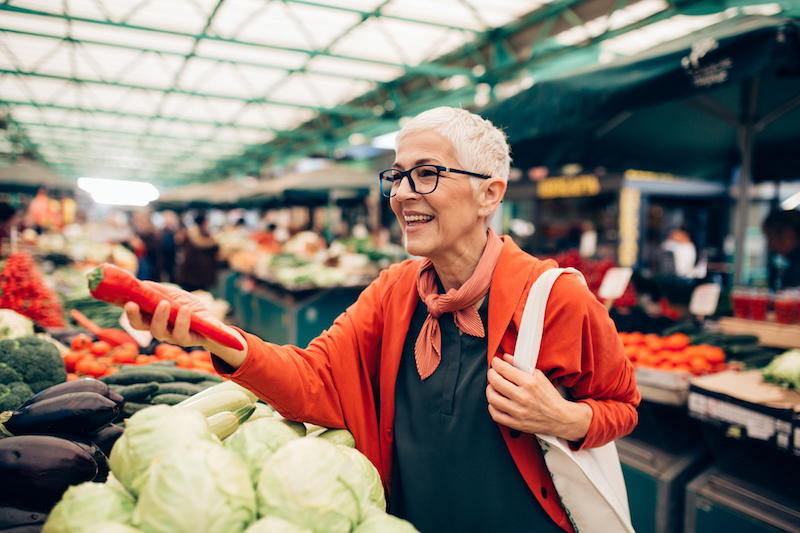 Senior woman buying vegetables at market
