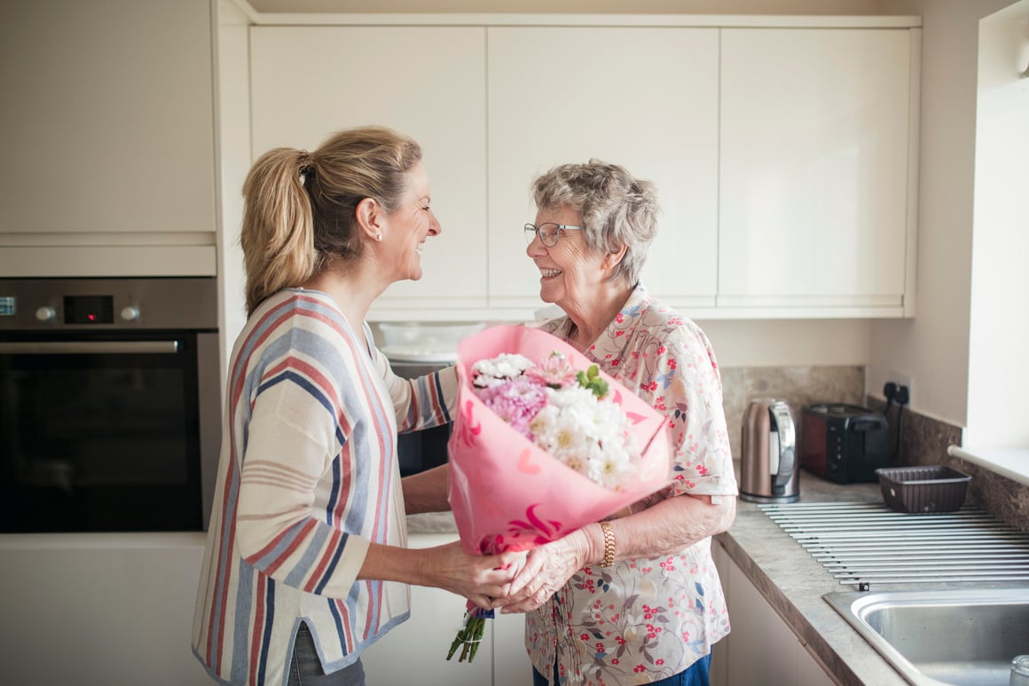 Woman giving flowers to senior woman